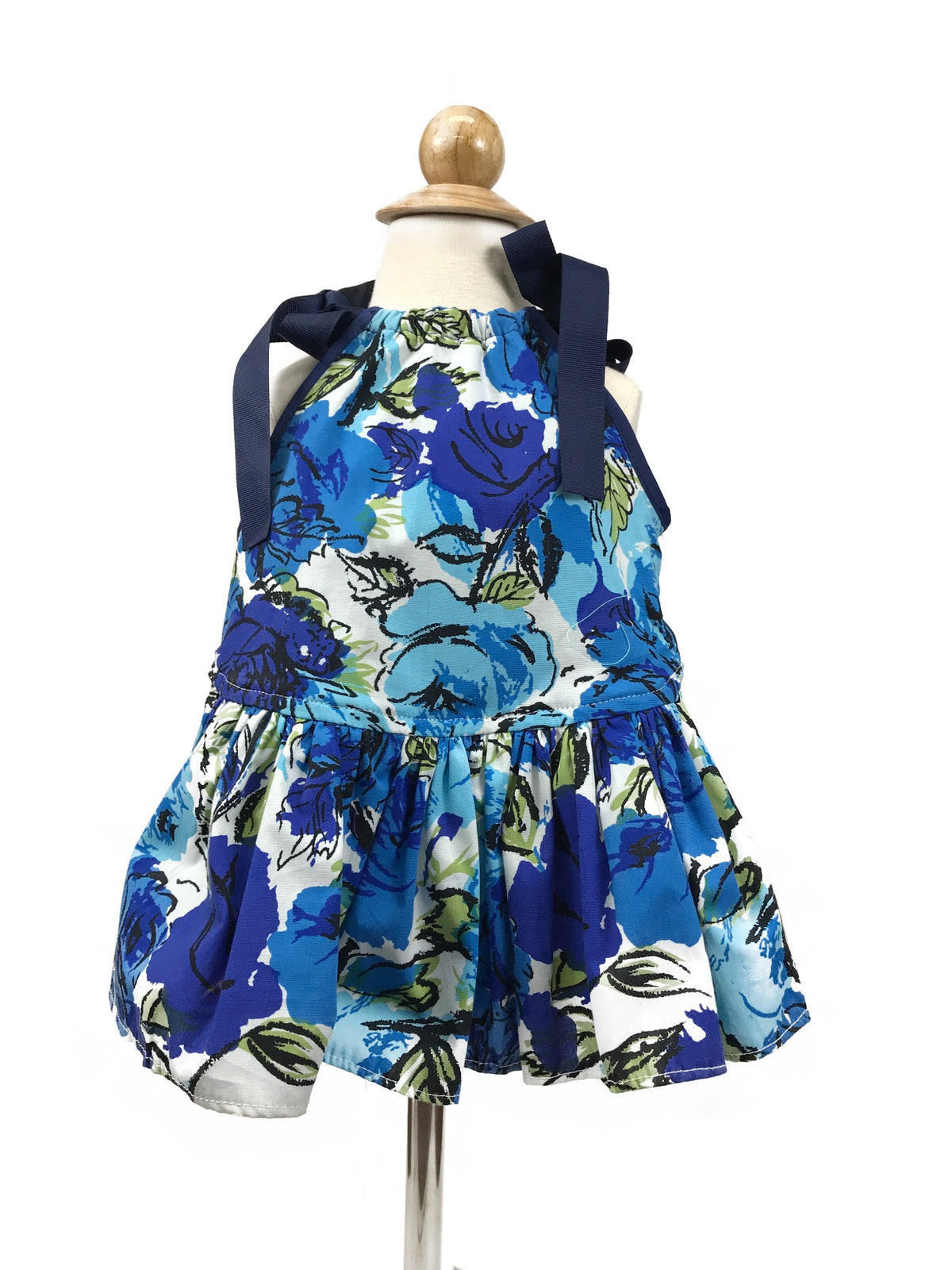 Blue rose floral dog sundress displayed on a dress form, featuring navy ribbon ties and a gathered skirt
