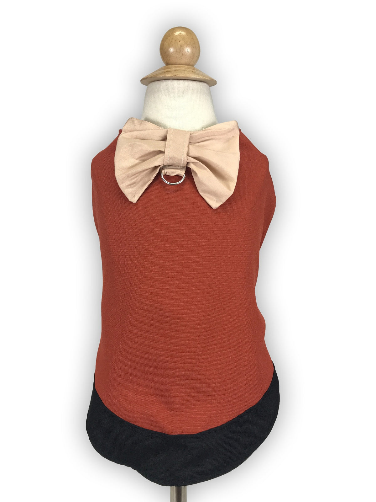Mannequin back view showing rust dog vest with large cream bow, metal ring detail, and rounded black hem