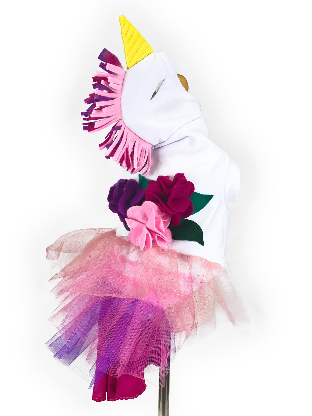 Mannequin side and back view showing yellow unicorn horn, pink and purple fringe mane, three decorative flowers, green leaves and layered pink-purple tulle skirt